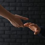 Changer le regard journalistique sur le suicide peut sauver des vies Woman giving hand to depressed man against dark background. Suic